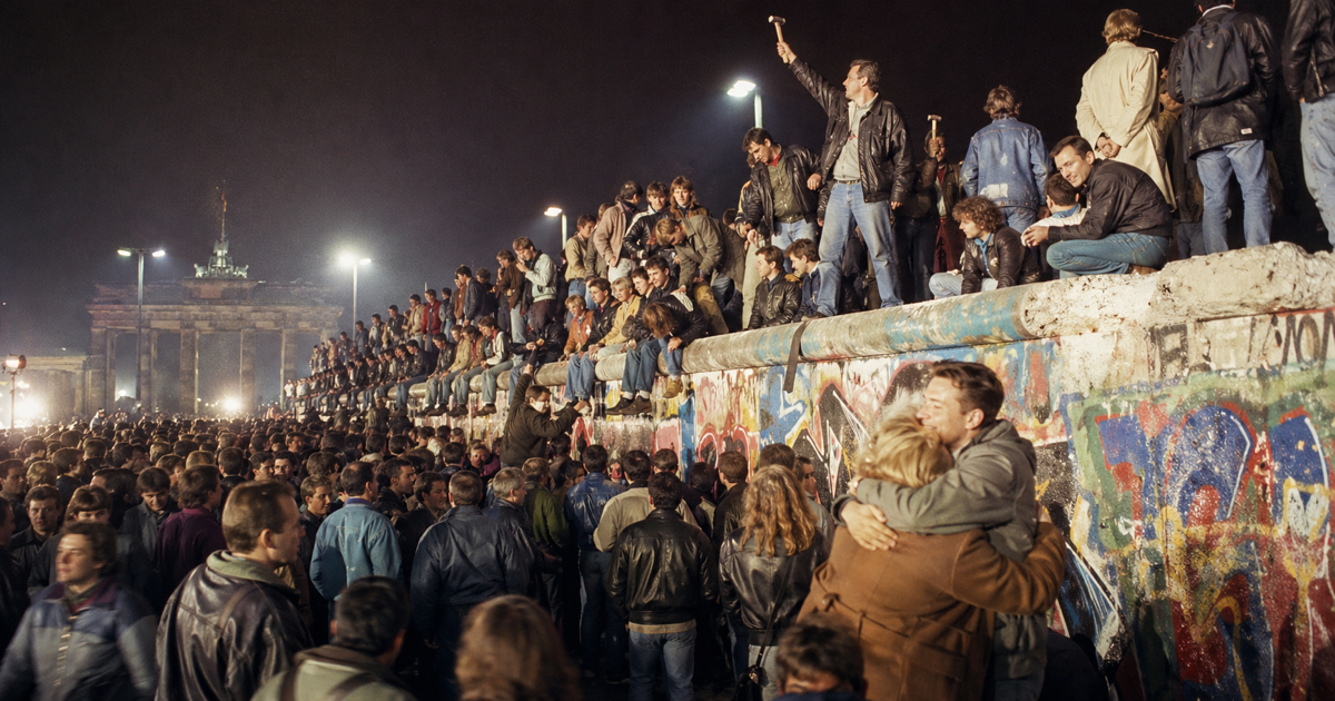 Persone sul Muro di Berlino durante una celebrazione notturna della sua caduta